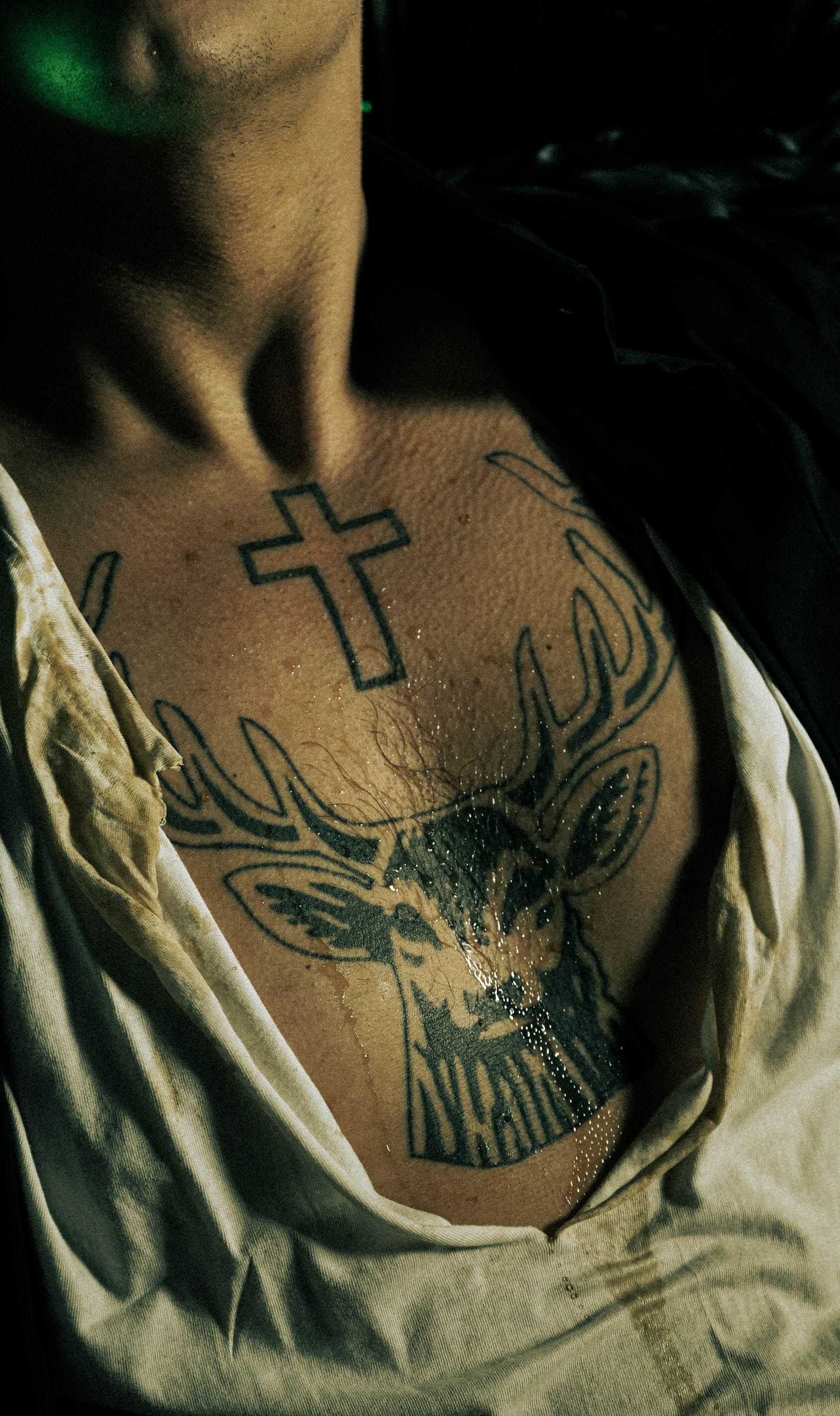 Tatuagem de veado e cruz no peito masculino